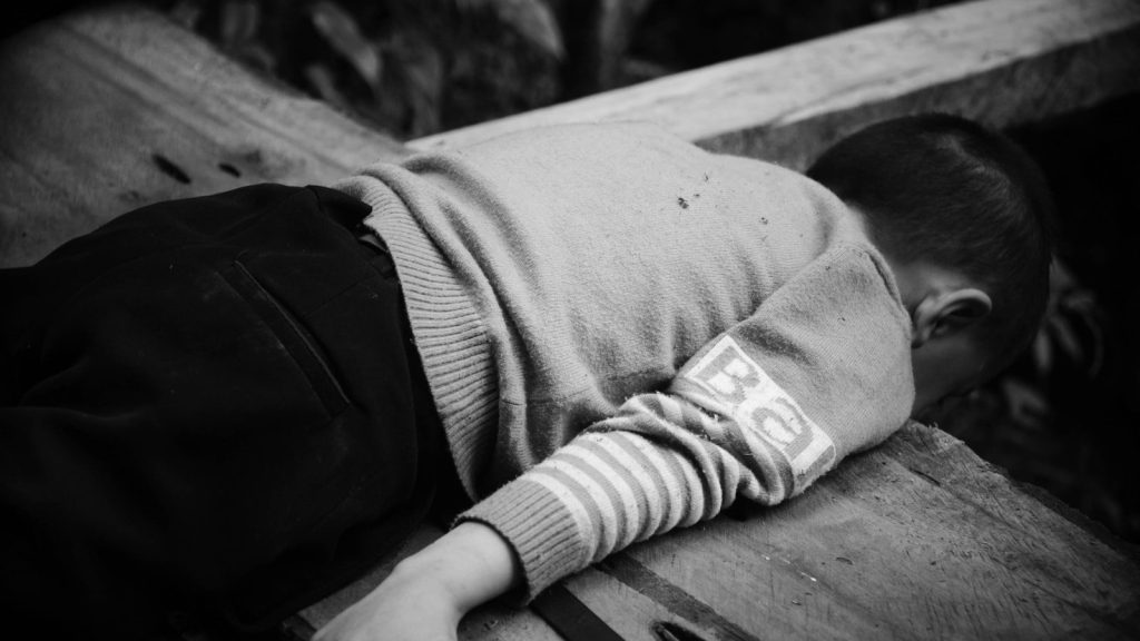 A boy lying on the bench.