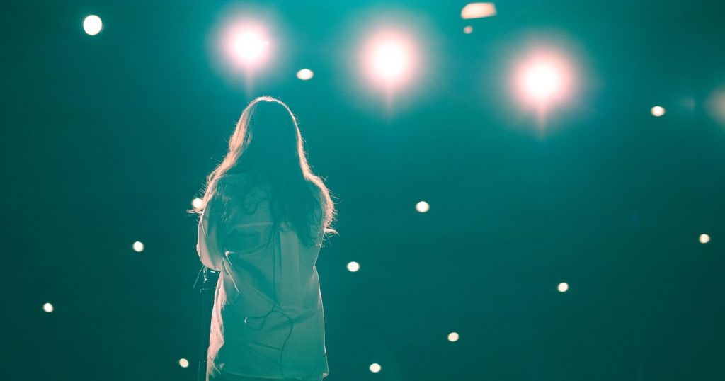 Silhouetted singer under stage lights.