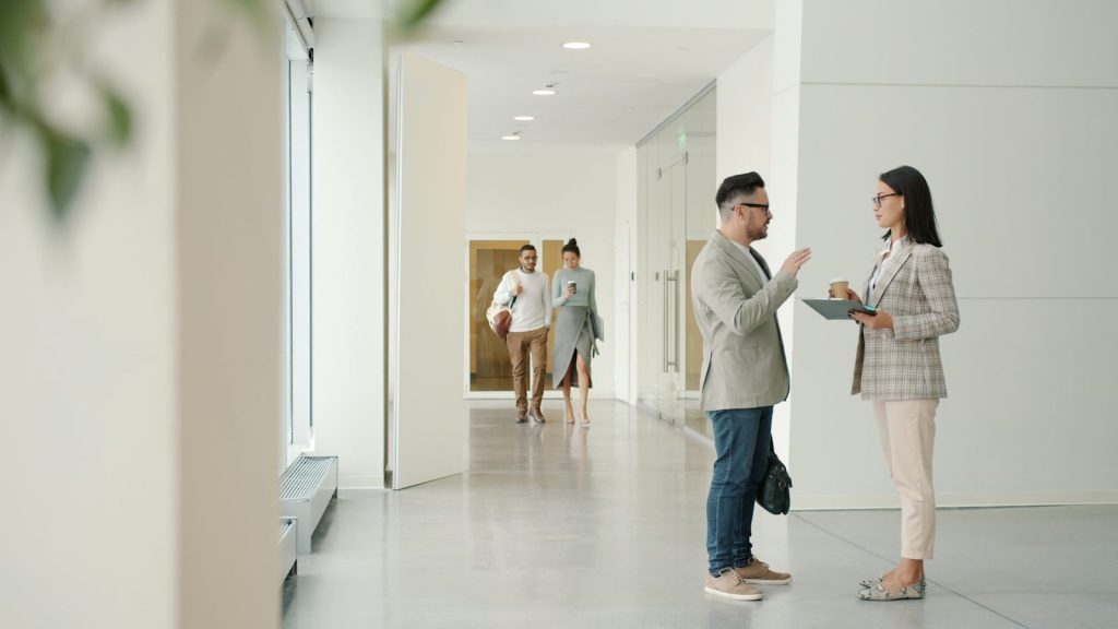 Employees talking in a modern office hallway.