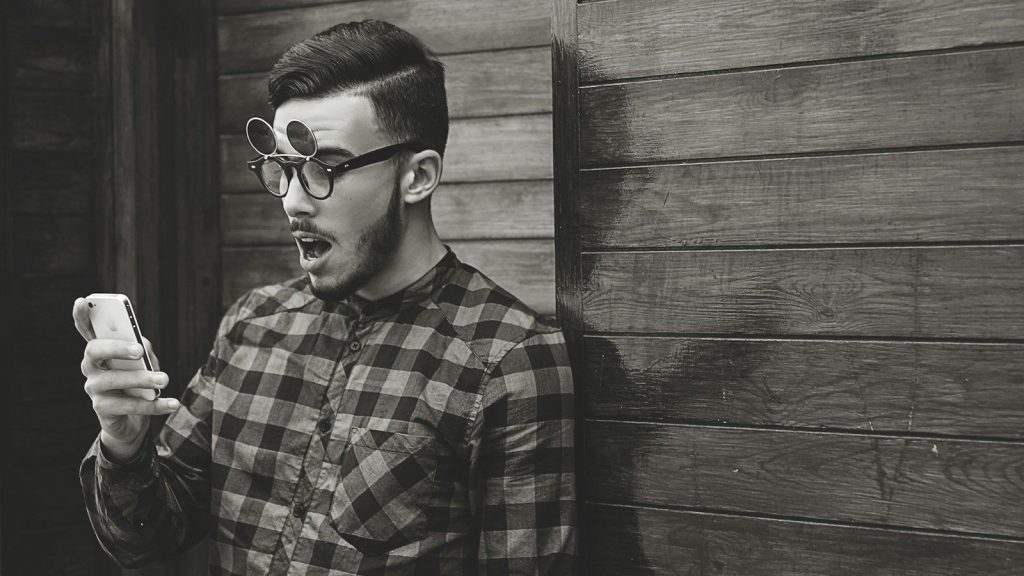 A man looking shocked while looking at his phone.