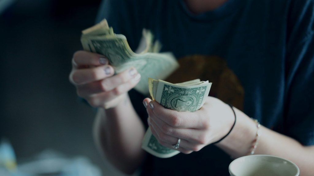 A person counting dollar banknotes.