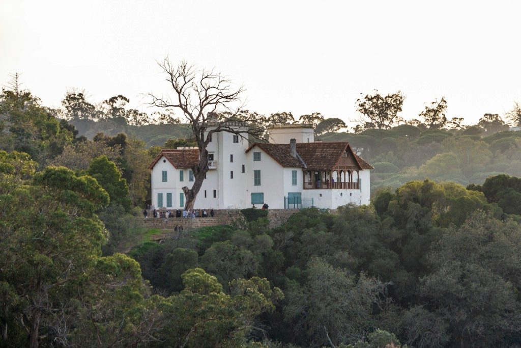A large white house sitting on top of a lush green hillside
