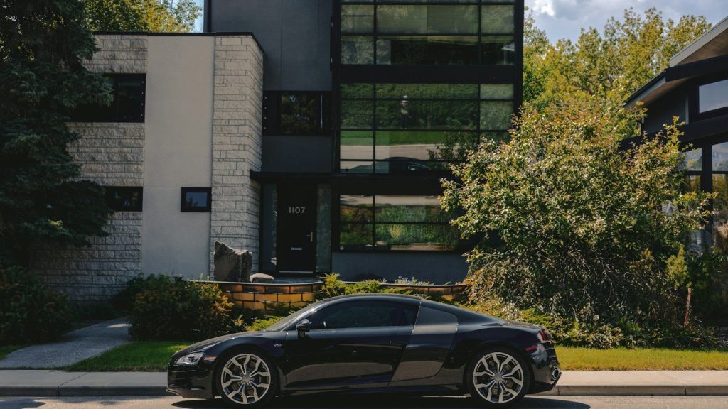 Modern luxury home with a sports car parked outside.