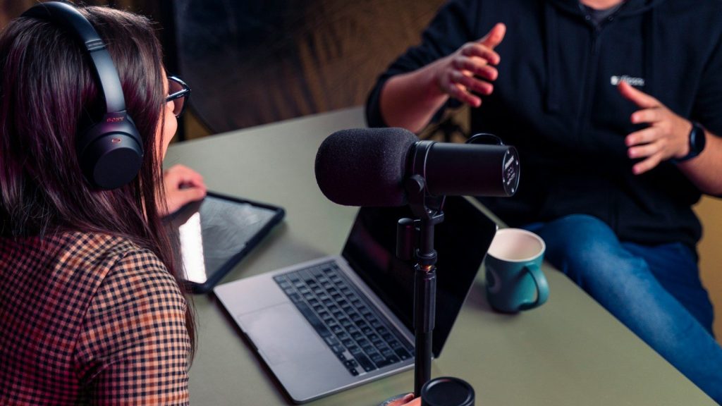 Podcast host interviewing a guest in a modern recording studio.