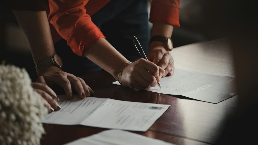 Person signing legal documents on a table.