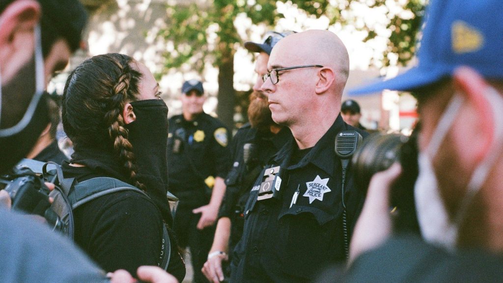 Police officer speaking with a civilian during a public incident.
