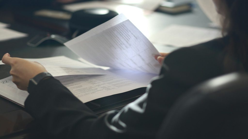 A woman sitting at a table reviewing legal documents.