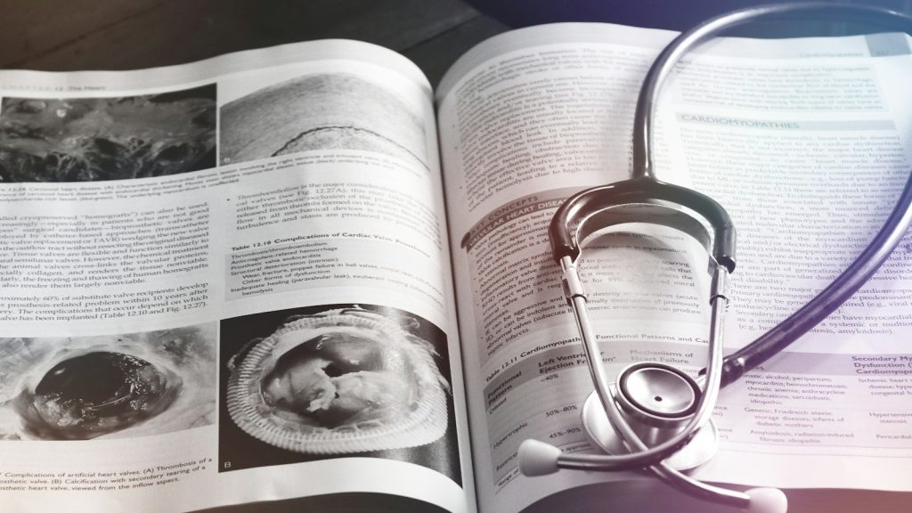 Stethoscope resting on an open medical book.