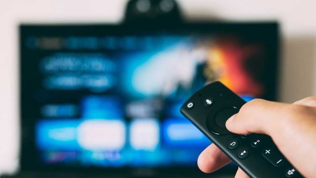 Person holding a TV remote while streaming content on a smart television.