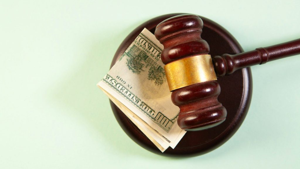 A gavel rests on a sound block with money.