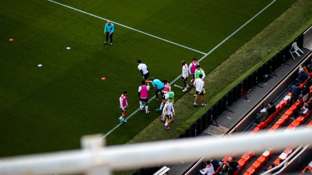 Soccer players gathered on the sidelines after a stadium match.