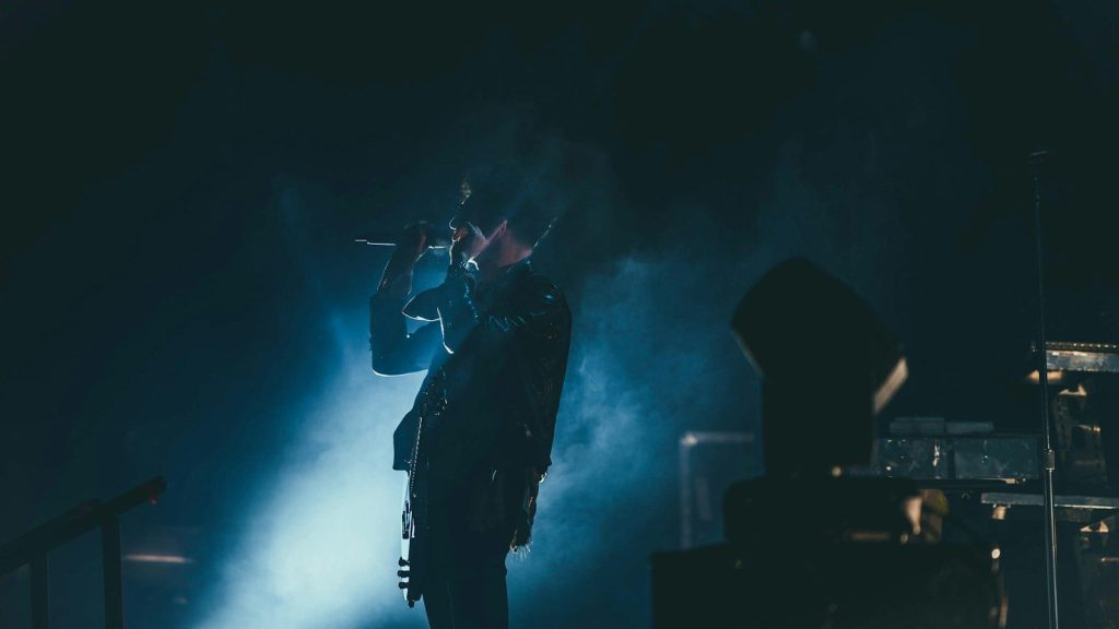 Musician performing live on stage with a microphone.