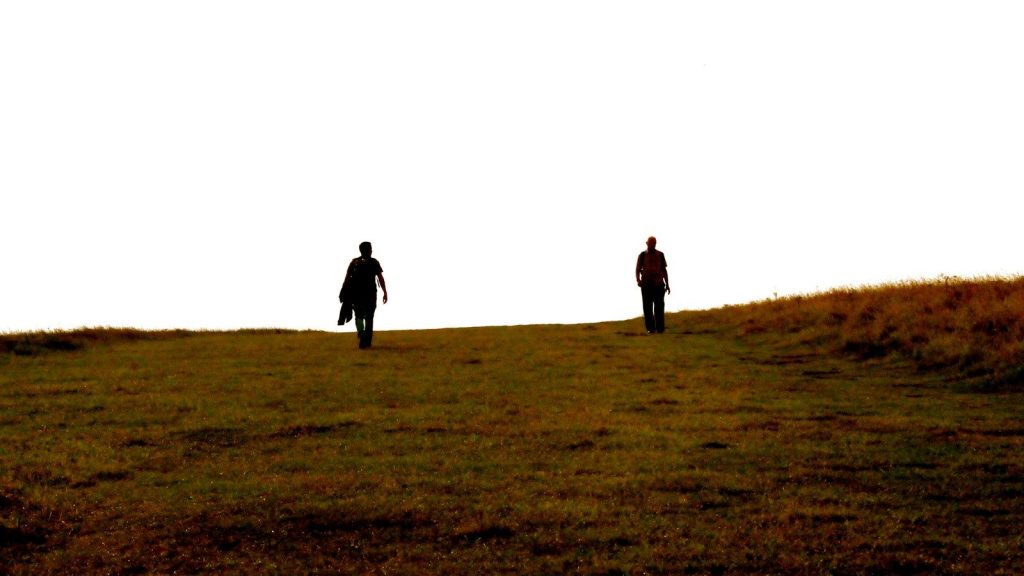 Two people walking apart across an open field.