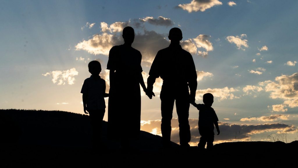 amily holding hands at sunset.