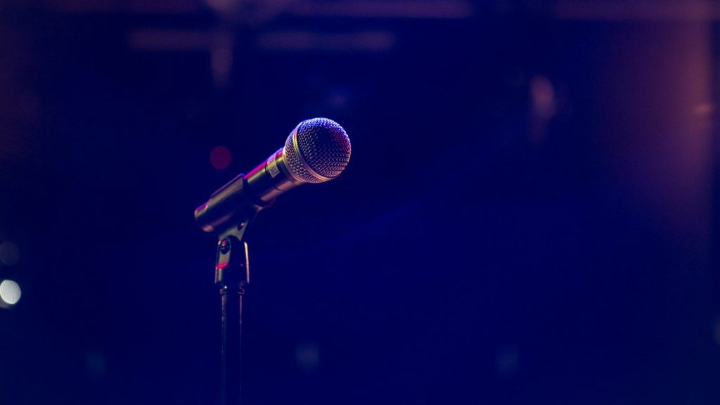 Microphone on a spotlight-lit concert stage.