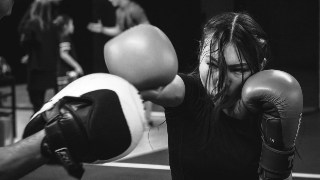A woman wearing boxing gloves throws a punch during a training session.