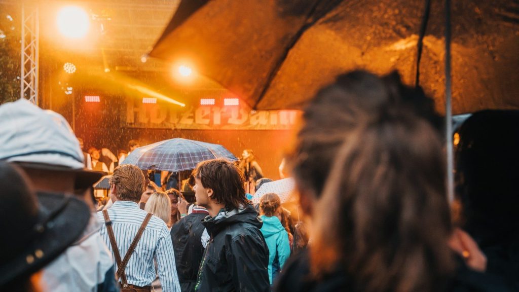 Concertgoers wait in the rain with umbrellas