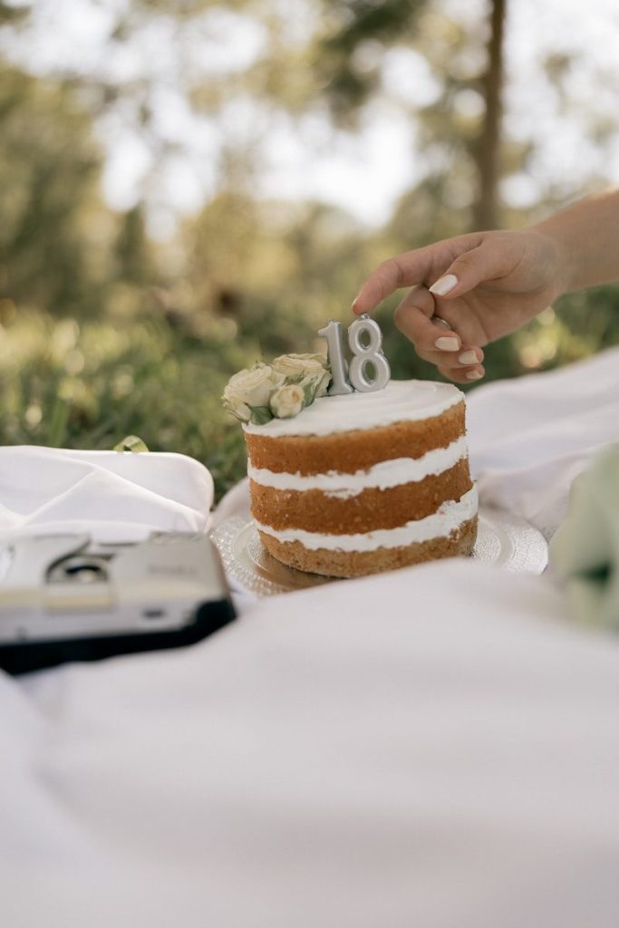 A naked cake decorated with flowers and number 18.